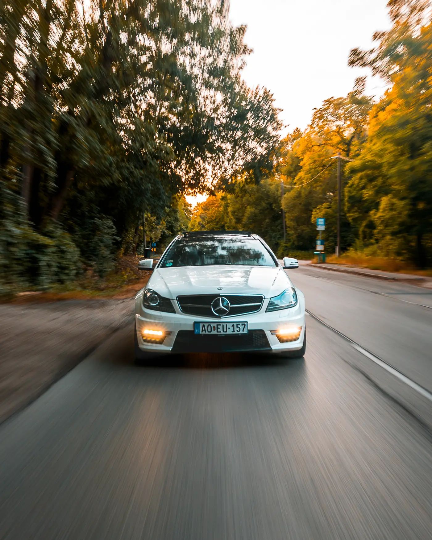 Mercedes-AMG C 63 from the front, headlights on, trees blurred on both sides