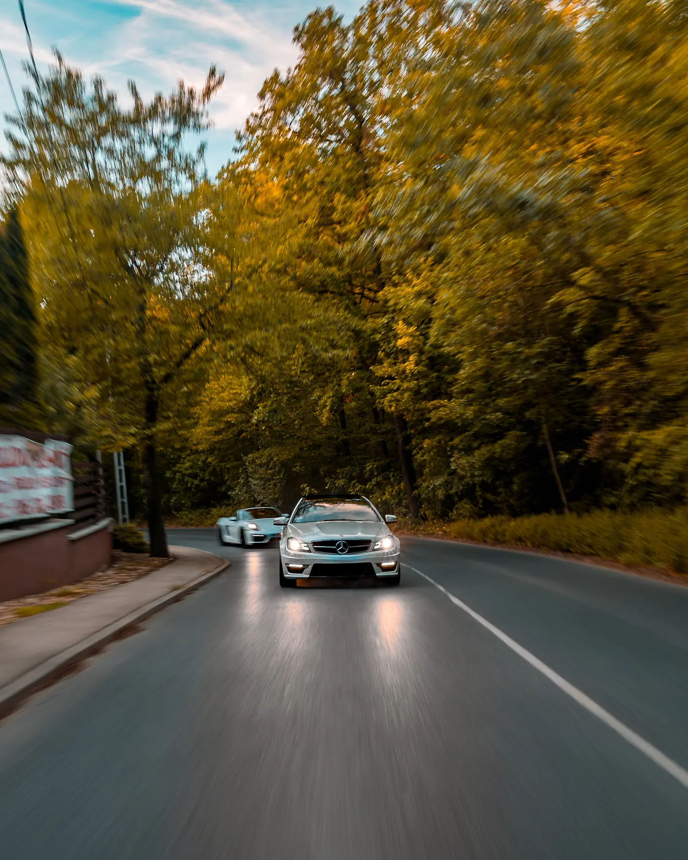 Mercedes-AMG C 63 leading the Boxster GTS along an autumn forest road