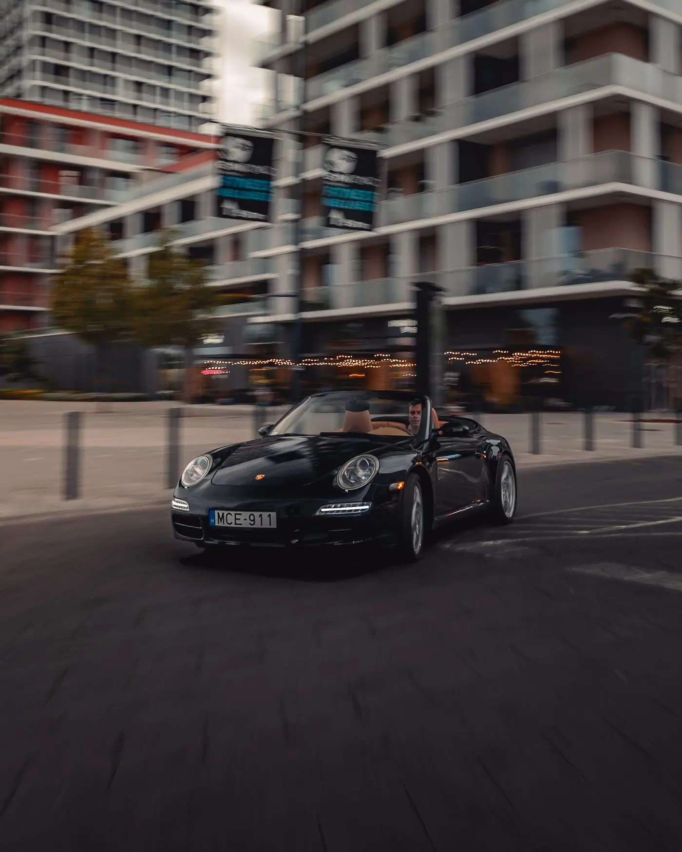Porsche 911 Carrera Cabriolet close up in a turn, apartment blocks blurred behind