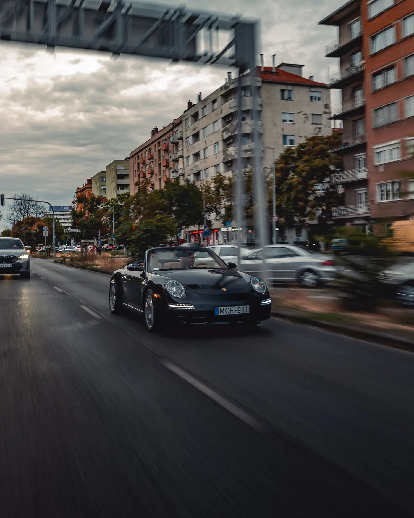 Porsche 911 Carrera Cabriolet in city traffic under an overhead sign gantry