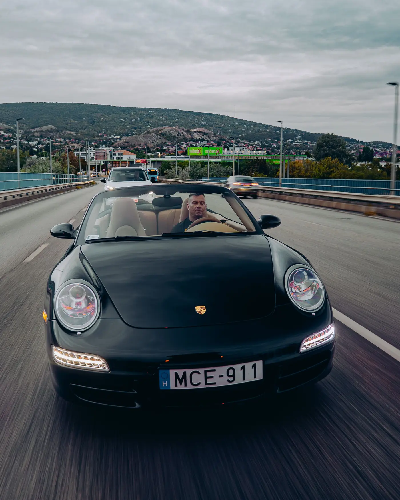 Porsche 911 Carrera Cabriolet close up from the front, hills and a cloudy sky behind